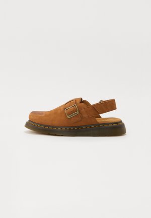 Brun ruskinds slingback-sko med justerbar spænde, polstret indersål og gummisål med kontrasterende gul syning.