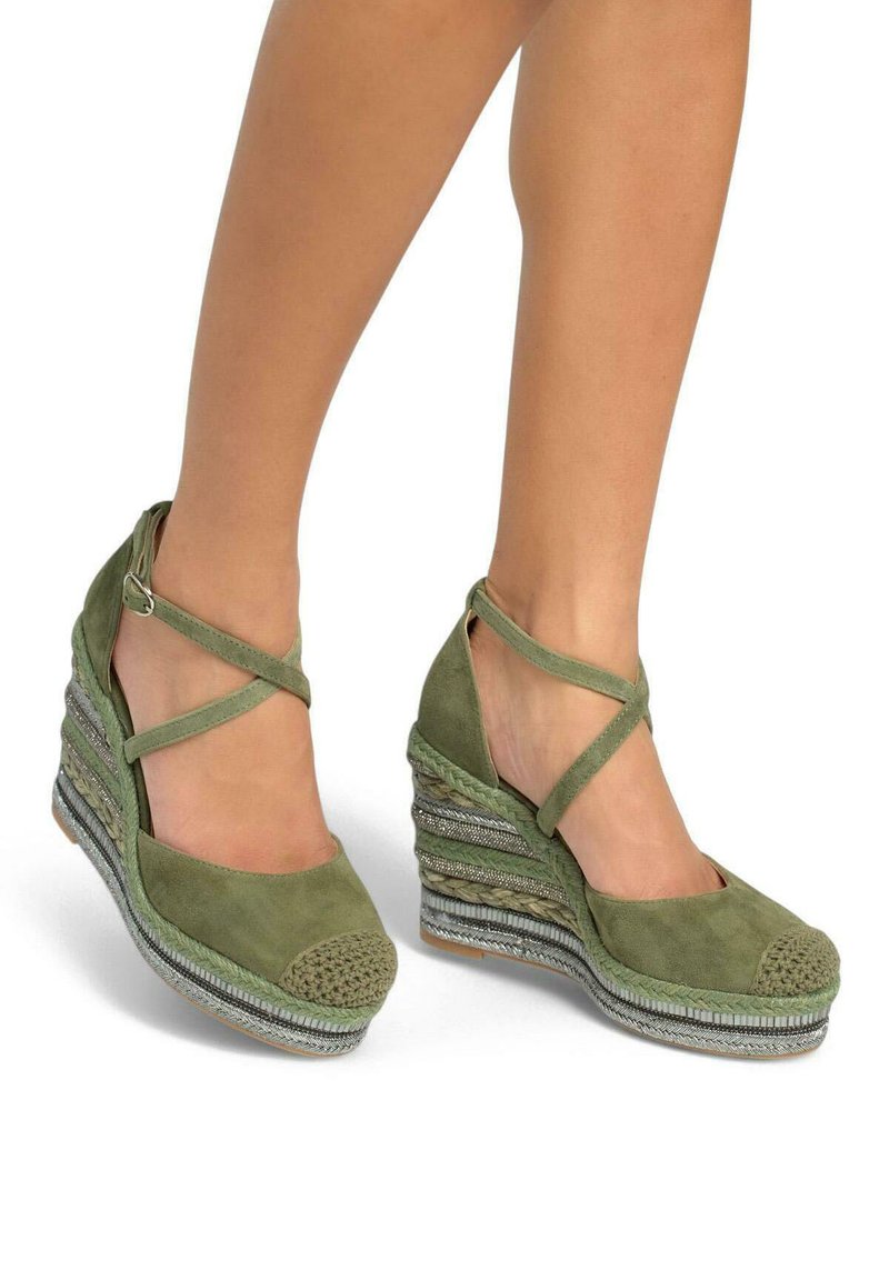 Sandales compensées en suède vert avec des brides chevauchantes autour de la cheville et une plateforme tissée texturée arborant des rayures métalliques et un détail en tressé.