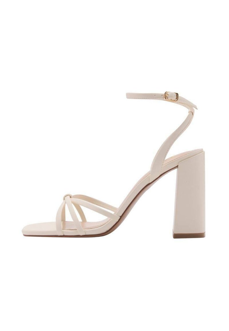 Ecrufarbene Sandalen mit Blockabsatz und dünnen Riemen, einer quadratischen Zehenpartie und einem verstellbaren Knöchelriemen. Glatte Textur und minimalistisches Design.