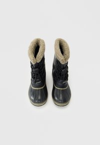 Botas de invierno negras con forro de felpa beige, suelas de goma y cordones, dispuestas una al lado de la otra sobre un fondo blanco.