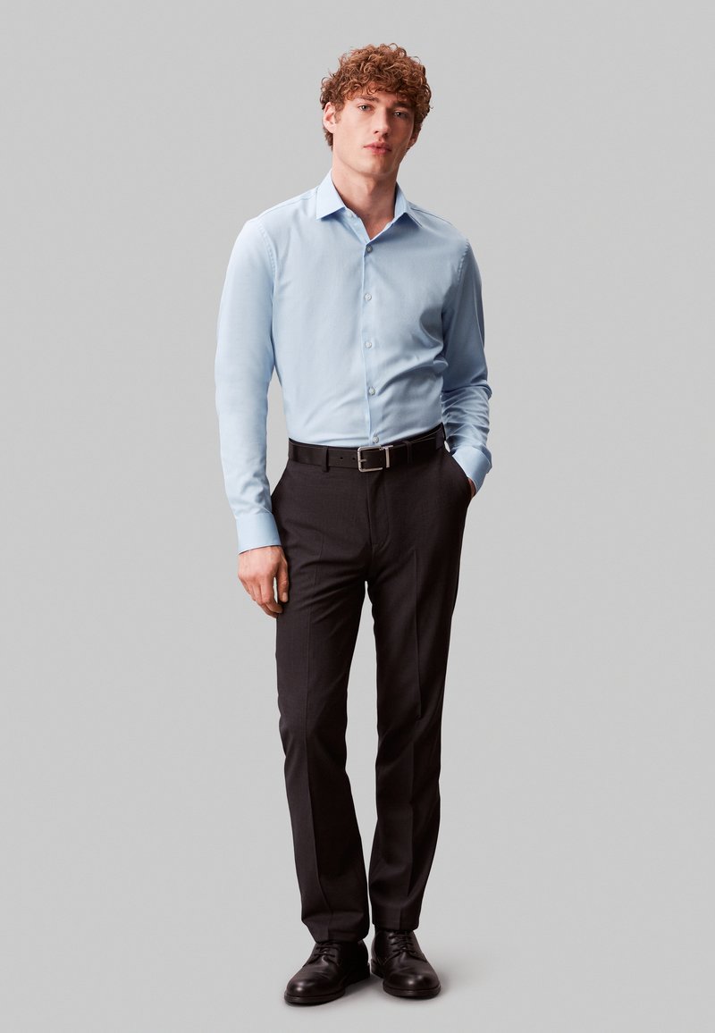 light blue dress shirt and black pants A timeless combo black pants & a sky blue shirt. Effortless, sharp, and made for business-class events., Pro-tip: never skip the belt and blazer. , Confidence isnt in the clothes, its in how you