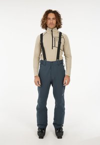 Skibroek in donkerblauw, gemaakt van waterdicht materiaal, met verstelbare zwarte bretels en een rechte snit; contrasterende beige bovenhelft.