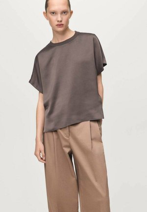 Brown short-sleeve top made of smooth fabric, paired with light brown wide-leg trousers featuring pleats and a relaxed silhouette.
