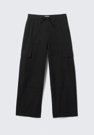 Μαύροι cargo παντελόνες με φαρδιά μπατζάκια, εμπρόσθιες τσέπες, τσέπες με καπάκι στους μηρούς, θηλιές για ζώνη και ζωνάκι με κορδόνι στη μέση, απλωμένοι επίπεδα σε λευκό φόντο.