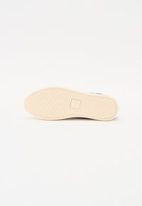 Suola di scarpa con fondo in gomma beige, caratterizzata da righe orizzontali per la trazione e una scatola centrale per il logo. Design pulito con bordi lisci.