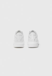 White sneakers with a smooth leather upper, rounded heel, and flat rubber sole. Features embossed logo on the heel and minimalistic design.