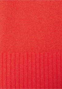Pull en tricot rouge avec une texture lisse et un ourlet côtelé. Le tissu est doux et tricoté uniformément partout.