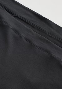 Czarne legginsy wykonane z miękkiego, elastycznego materiału. Charakteryzują się gładką fakturą i płaskim, równym przeszyciem wzdłuż szwów. Prosty design.