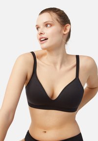 Sujetador inalámbrico negro con diseño de escote en V profundo. Fabricado con tejido suave, con tirantes ajustables y un detalle de costura mínimo.