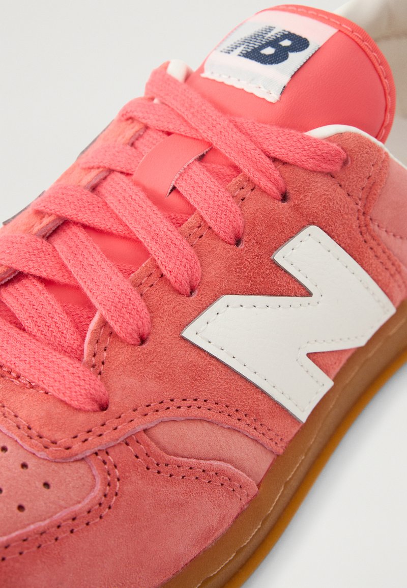 Las zapatillas de ante en color coral presentan un logotipo 'N' en cuero blanco, cordones a juego, puntera perforada y una suela de goma para proporcionar tracción.