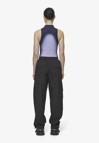 Pantalons cargo noirs avec plusieurs poches, associés à un bodysuit sans manches dégradé passant du violet foncé au violet clair. Chaussures noires.