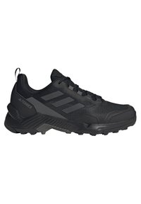 Černá sportovní bota s síťovinovým svrškem, gumovou podrážkou a texturovanými detaily. Disponuje třemi postranními pruhy, šněrováním a zadním poutkem.