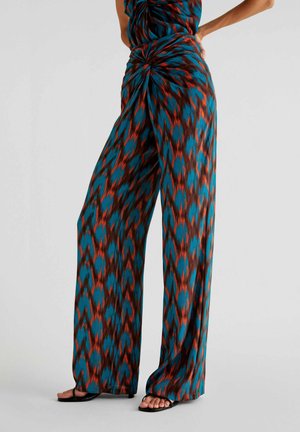 Pantalons largeur totale dans un motif ikat teal, rouge et marron. Tissu doux avec un détail de nœud tordu à la taille, design jusqu'au sol.