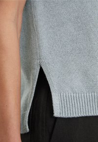 Lyseblå strikket sweater med ribkant og sideslids, der har en blød tekstur og et afslappet design.
