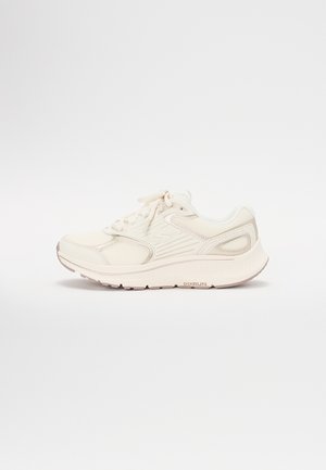 Białe buty sportowe z siateczkową cholewką, wyściełanym kołnierzem i szarymi akcentami. Oferują teksturowaną podeszwę oraz system sznurowania zapewniający pewne dopasowanie.