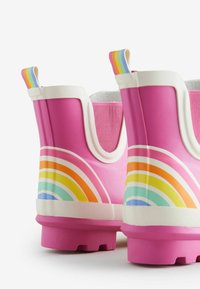 Stivali da pioggia in gomma rosa con dettagli bianchi e design arcobaleno. Presentano cuciture arrotondate, suole testurizzate e fodera in tessuto sulla parte alta.