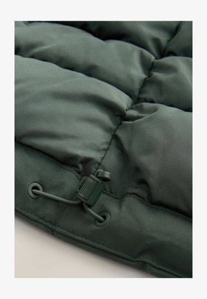 Dark green puffer jacket section featuring quilted design, smooth texture, and an adjustable drawstring with plastic hardware at the hem.