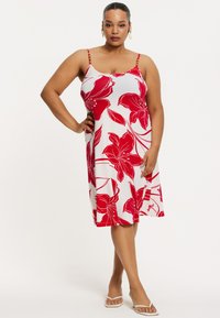 Robe à imprimé floral rouge et blanc avec des bretelles fines, une coupe décontractée et une longueur jusqu'aux genoux. Présente des accents perlés sur les bretelles.