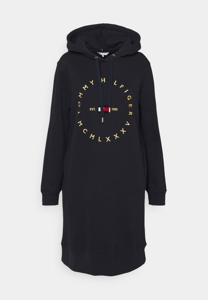Vestido tipo sudadera negro con mangas largas, capucha con cordón y texto circular dorado "Tommy Hilfiger" que rodea un pequeño logo de bandera en rojo, blanco y azul.