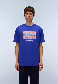 Royal blue cotton t-shirt featuring a stylized Icelandic flag graphic in red, white, and blue with "NAPAPIJRI" text below in white.