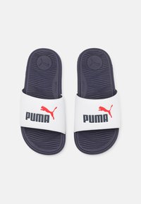 Rutschsandalen mit weißen synthetischen Riemen, die mit schwarzem "PUMA"-Text und rotem Logo versehen sind, auf einer strukturierten navyblauen Gummisohle.