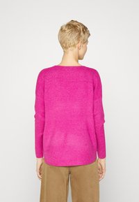 Fuchsia gebreide trui met lange mouwen en een ronde halslijn; zachte textuur en losse pasvorm; bekeken vanaf de achterkant, met een weergave van het schouderontwerp.