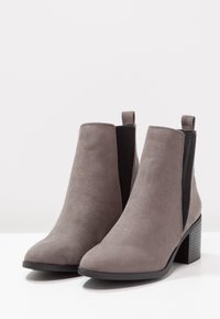 Grijze suede enkellaarsjes met een blokhak, elastische zijkanten en een gladde afwerking, met een ronde neus en een lussen. 