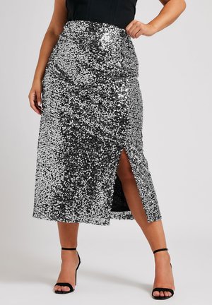 Gonna midi in paillettes argento con spacco alto e design a vita arricciata, caratterizzata da una fodera liscia e una texture lucida. Tacchi neri con lacci.