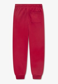 Punased dressipüksid elastse vöökohaga, mansettidega pahkluude juures ja ühe tagataskuga. Valmistatud pehmest, tekstuurse kangaga.