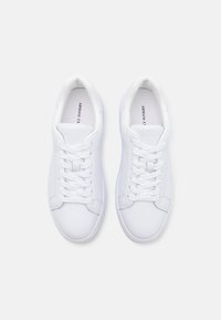White sneakers made of smooth leather, featuring flat laces, a rounded toe, and subtle stitching details. Brand name visible inside.