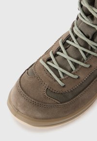 Bruine suède en mesh sneaker met groene veters, ronde neus, textuuraccenten en rubberen zool. Bevat versterkte stiksels.
