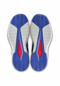 Sport Schuhsohlen mit blauen Gummi, die Zickzackmuster aufweisen, weißen Akzenten und einem roten dreieckigen Detail mit einem Logo in der Mitte.