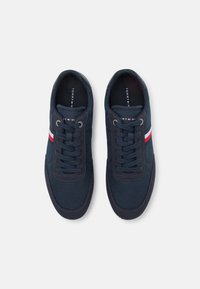 Marina blå sneakers med en strukturerad ovandel, snörning och röd- och vitrandig accent. Gummisulor och vadderad plös för komfort.