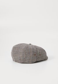 Houndstooth cap made of textured fabric, featuring dark brown, cream, and black patterns. Rounded shape with a small top button.
