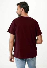 Bordowa koszulka z miękkiej bawełny, z krótkimi rękawami i luźnym krojem. Tył posiada prosty wzór z metką przy brzegu.