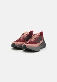Scarpe da ginnastica color amaranto e rosa con strisce nere, parte superiore in rete testurizzata, tallone rinforzato e una spessa suola grigia con battistrada resistente.