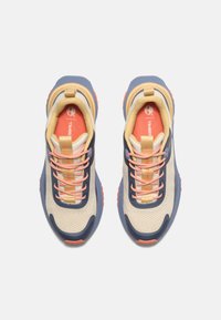 Beige og marineblå joggesko med mesh-stoff, oransje detaljer og en teksturert såle. Har justerbare lisser og forsterket hæl.