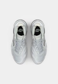 Hellgraue Sportschuhe mit einem strukturierten Synthetik-Obermaterial, runder Zehenpartie und Gummisohle mit Fischgrätenmuster. Die Schnürsenkel sind grau.