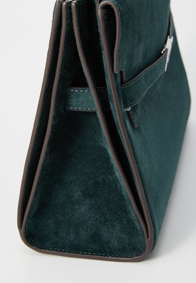 Teal ruskinds håndtaske med en struktureret design, der har en syet brun kant og en lynlåslukning. Glat tekstur med rene linjer.