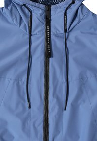 Veste à capuche bleu clair avec une fermeture éclair frontale noire, des cordons de serrage noirs, et le texte « Cecil Outerwear » sur la tirette de la fermeture éclair et aux extrémités des cordons.