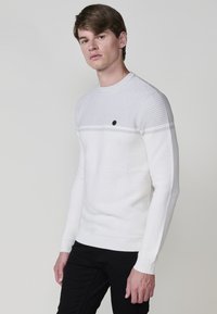 Textuur witte trui met een horizontaal streepdesign, ronde hals en een klein zwart logo op de borst. Slim fit silhoutte.