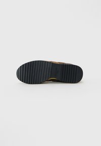 Shoe sole with deep horizontal grooves in black rubber, featuring "Blauer USA" branding in the center, photographed on a white background.