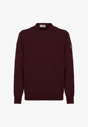 Maglione lavorato a maglia bordeaux con colletto tondo, maniche lunghe e polsini a coste. Presenta una toppa con il logo sulla manica sinistra. Texture morbida.