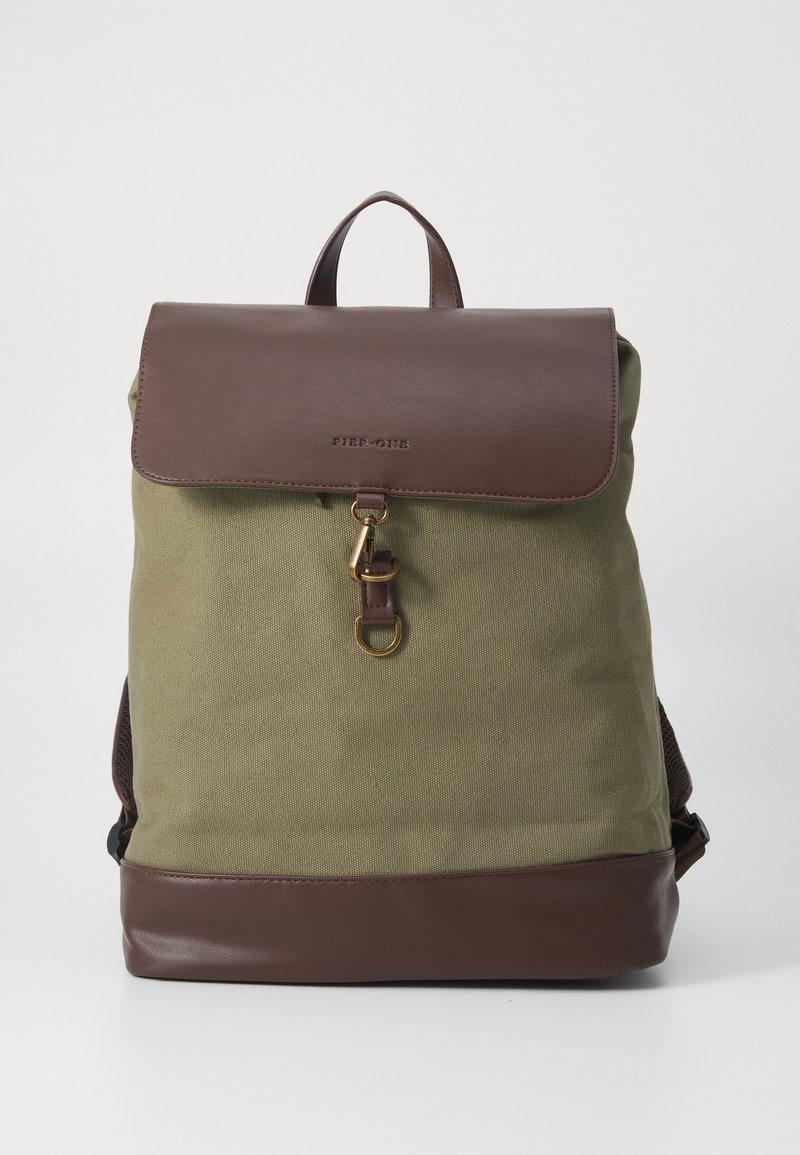 Zaino in tela di colore verde oliva con pattina e base in pelle marrone, dotato di una chiusura in oro e di una maniglia superiore per il trasporto.