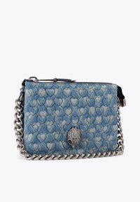 Sac bandoulière en denim avec un motif matelassé en forme de cœur, une sangle en chaîne argentée et un accent en métal argenté en forme de main.