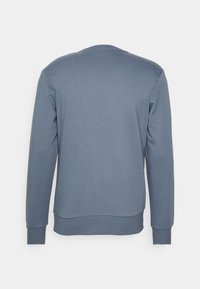 Felpa grigia con maniche lunghe, collo a giro e polsini a coste. Texture liscia e design semplice, senza motivi o decorazioni.