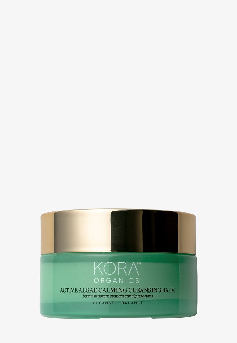 Pot en verre vert avec un couvercle doré, étiqueté "Baume Nettoyant Apaisant à l'Algue Active". Texte en noir, présente une texture lisse, un design épuré.