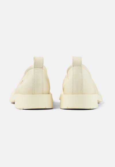 Beige leather slip-on shoes with a smooth texture, rounded shape, and low rubber soles; features a small heel tab at the back.