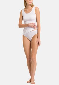 Hvid tanktop og matchende briefs, lavet af glat stof. Tanktoppen har brede stropper og en rund udskæring. Briefsene har en mid-rise skæring.