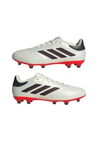Botas de fútbol blancas con una textura suave, que presentan rayas negras y acentos rojos. Incluyen un perfil bajo y un detalle en el talón negro.
